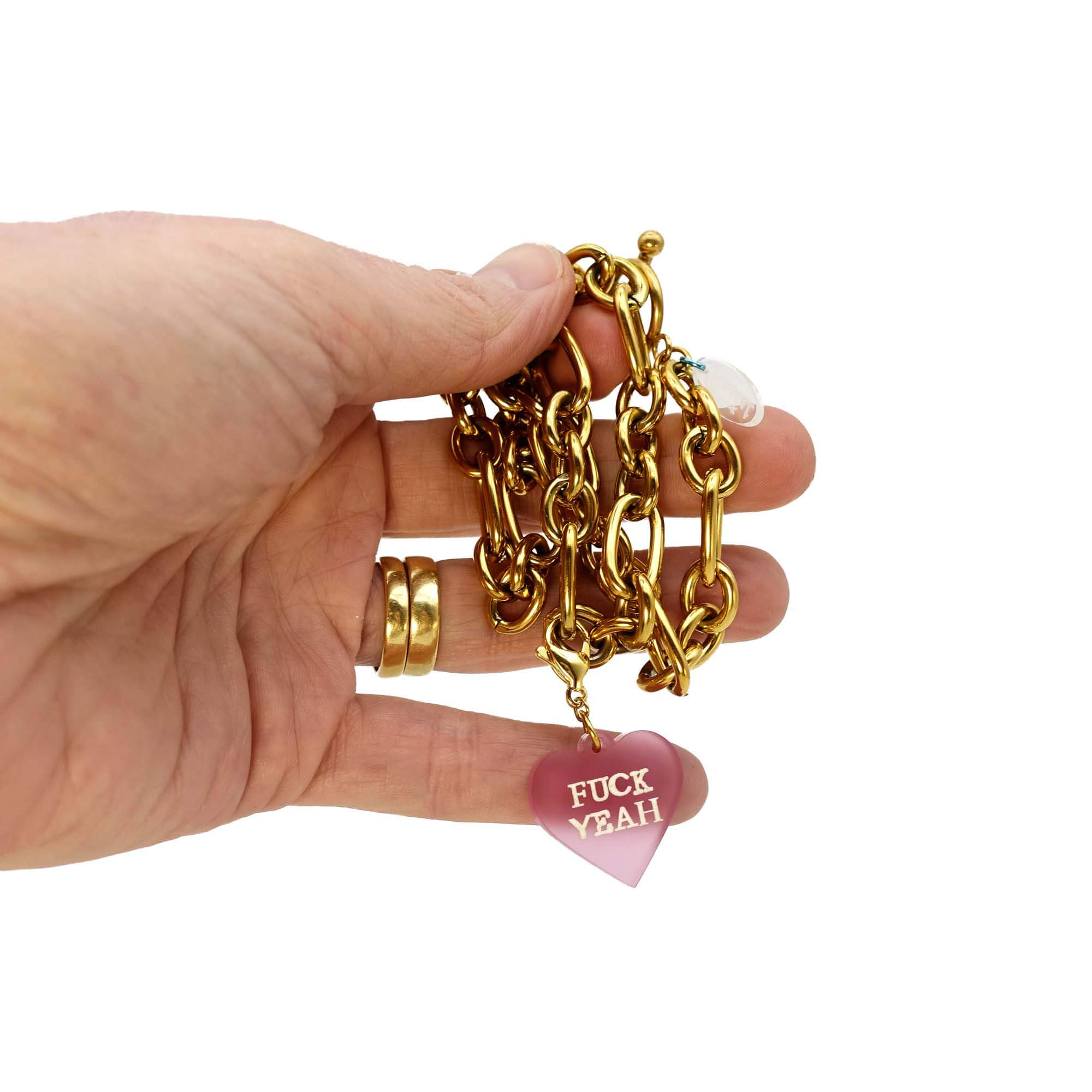 Sarah holds a gold plated chunky chain charm choker with a pink F*ck Yeah heart charm. 