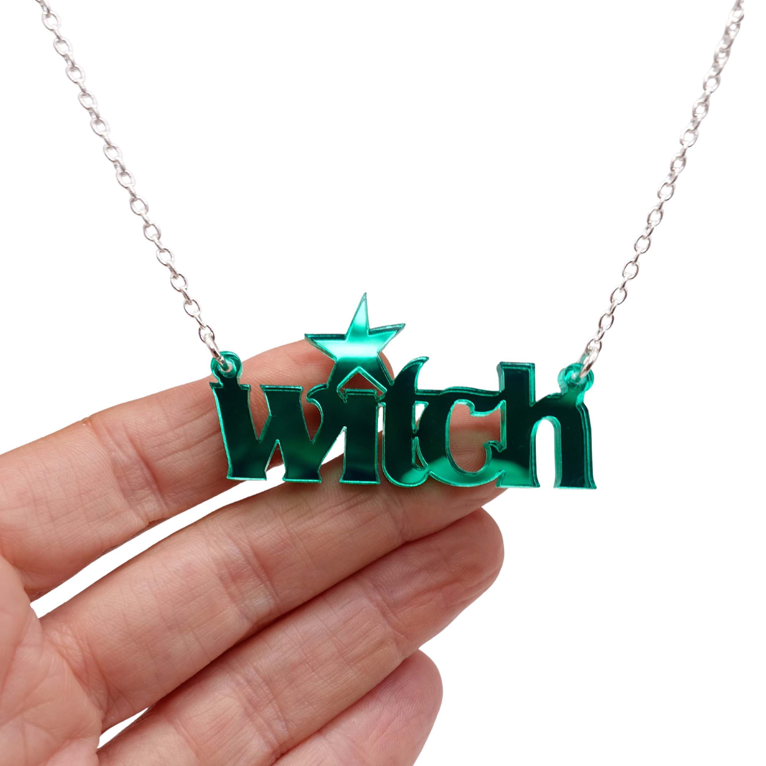 Witch necklace in electric green mirror shown hanging against a white background with my hand for size.