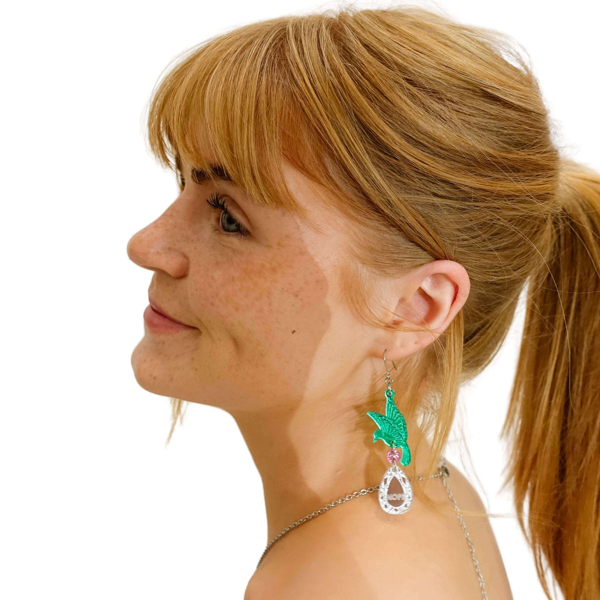 Eliza wears the RUDE BIRD earrings in green with birds holding silver 'jewels' that say 'Nah' and 'Nope'. 