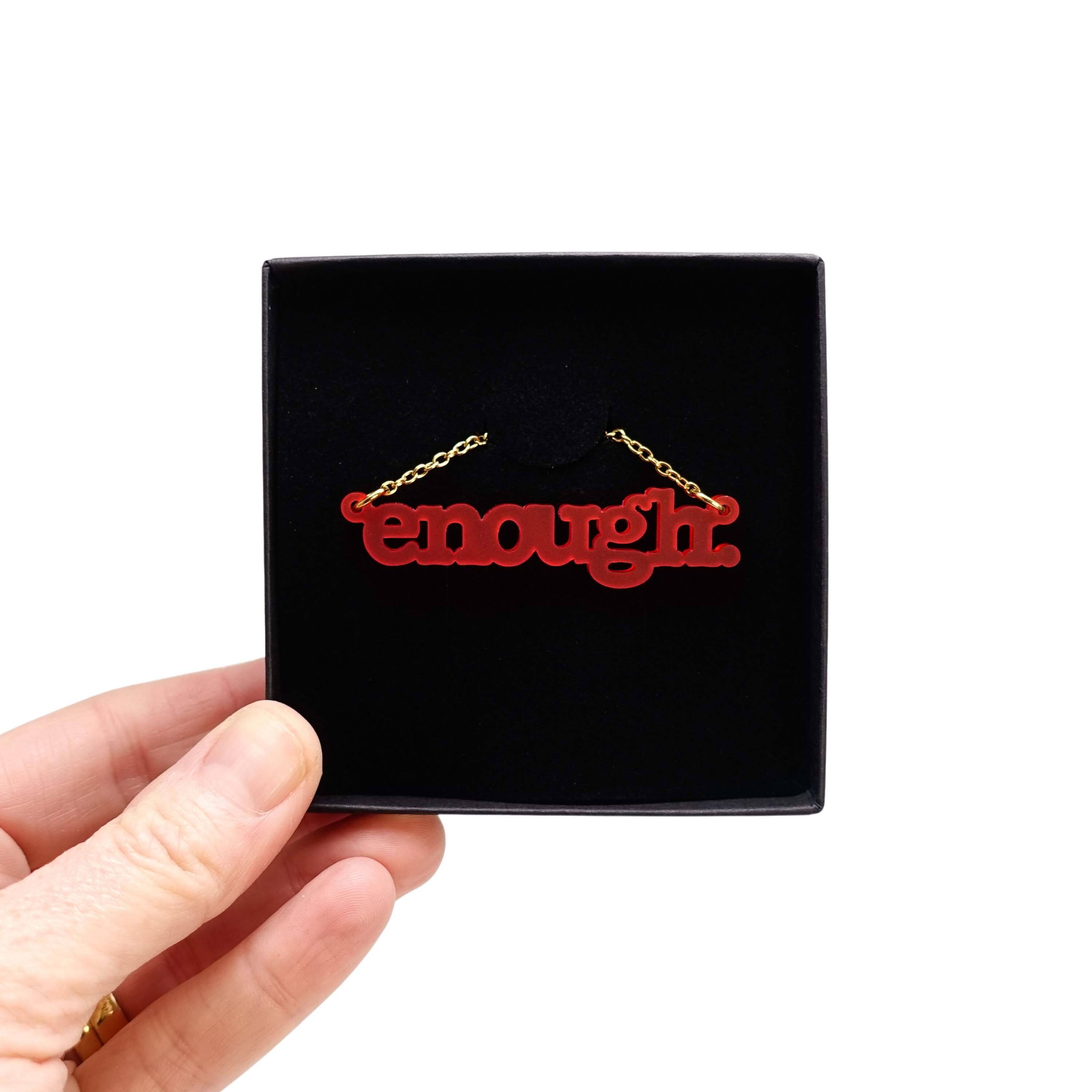 Typewriter Enough necklace in chilli frost shown held up in a Wear and Resist gift box. 