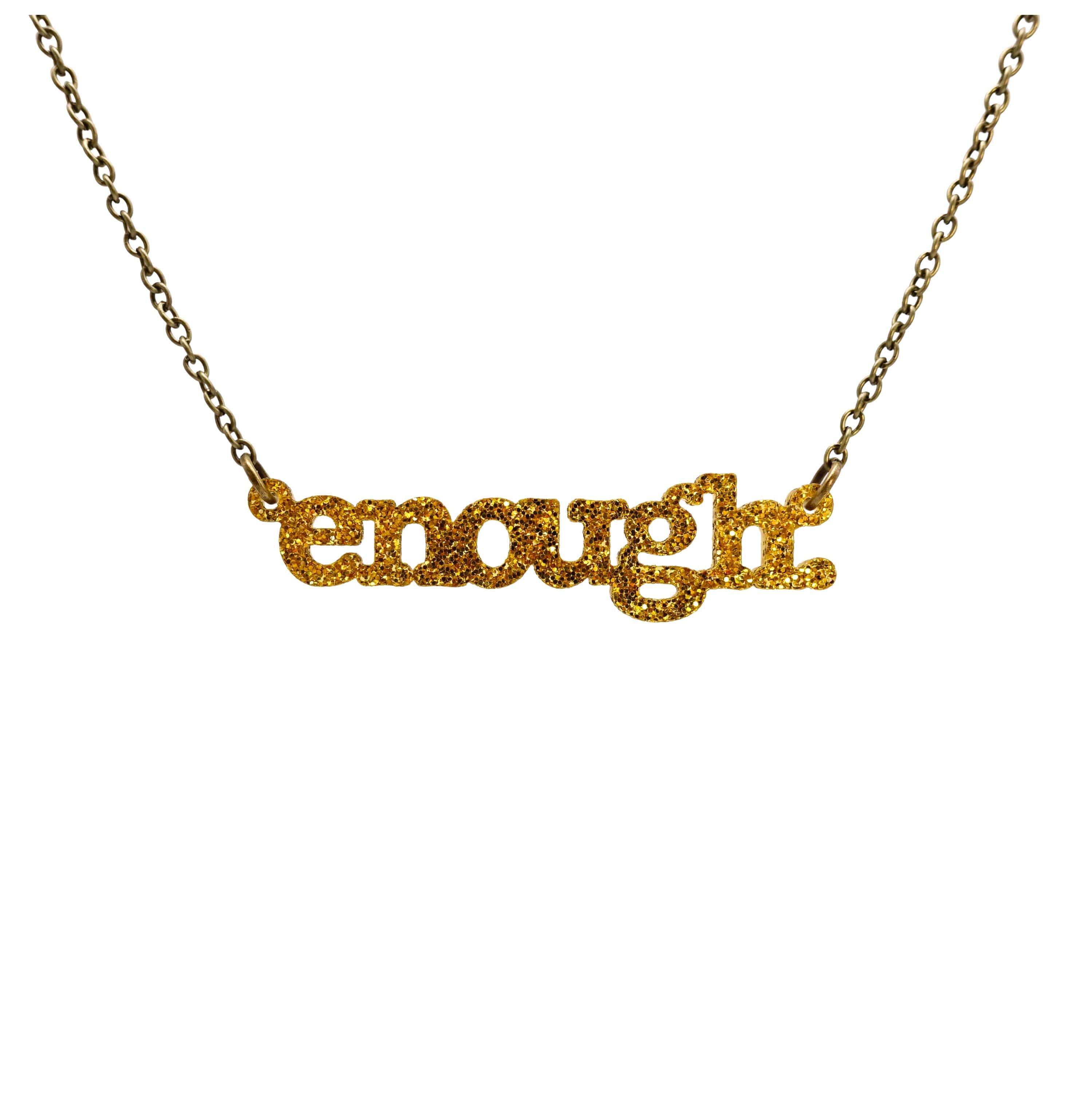 Typewriter Enough necklace in ultra gold glitter shown hanging on an antique gold chain against a white background. 