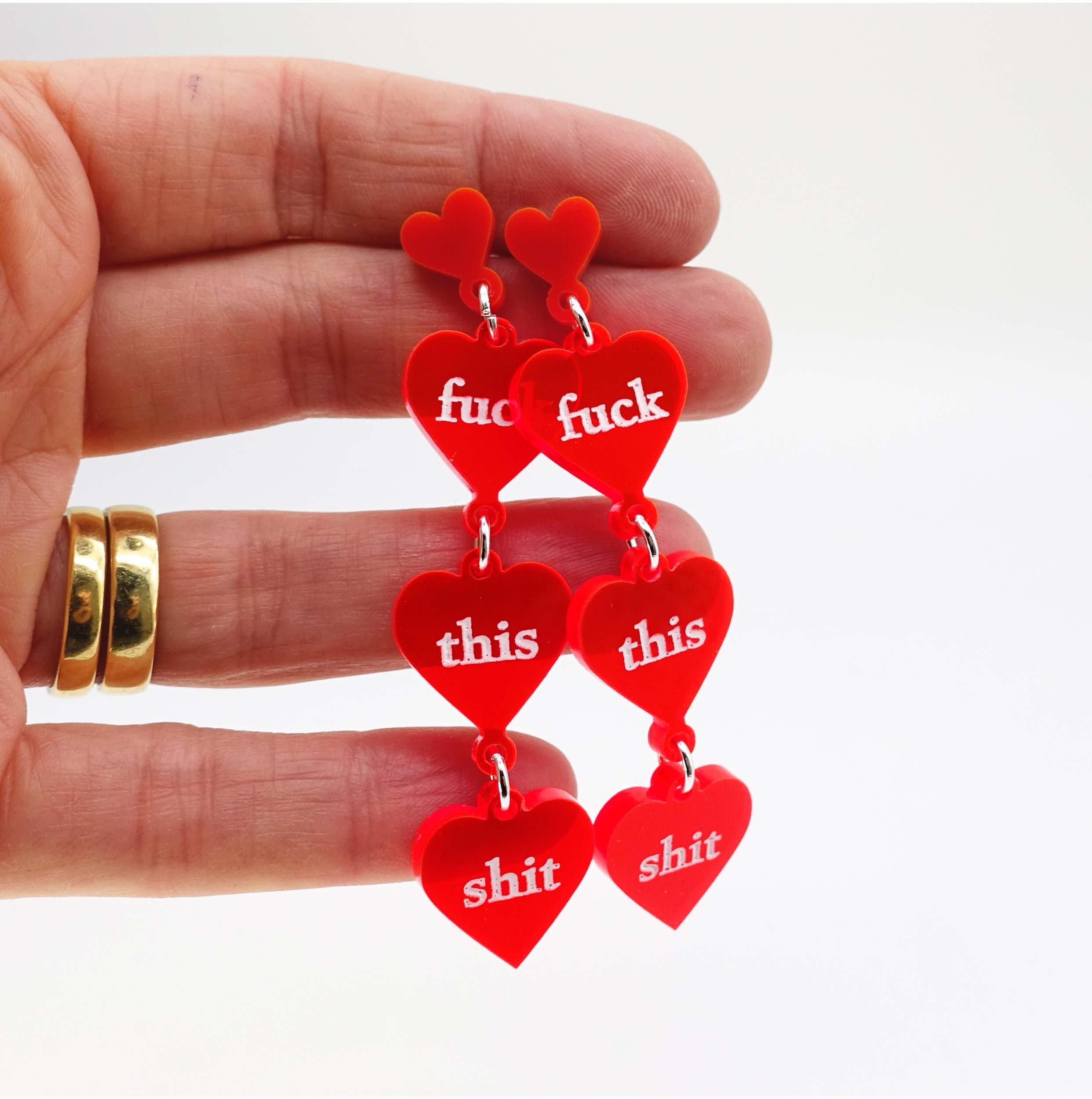 Hot red f*ck this sh*t heart earrings being held up for scale. 