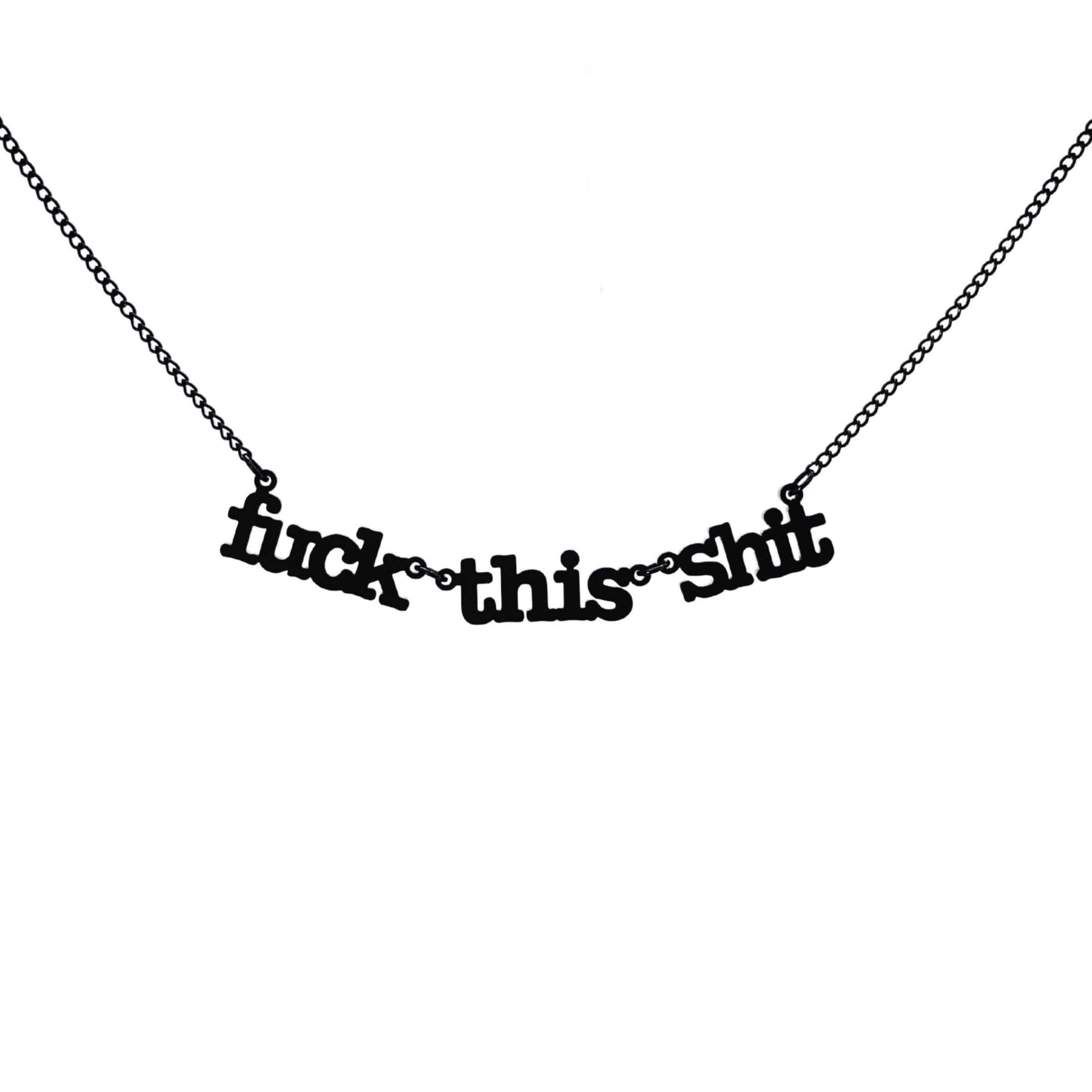 F*ck this sh*t necklace in matte black shown hanging against a white backround. 