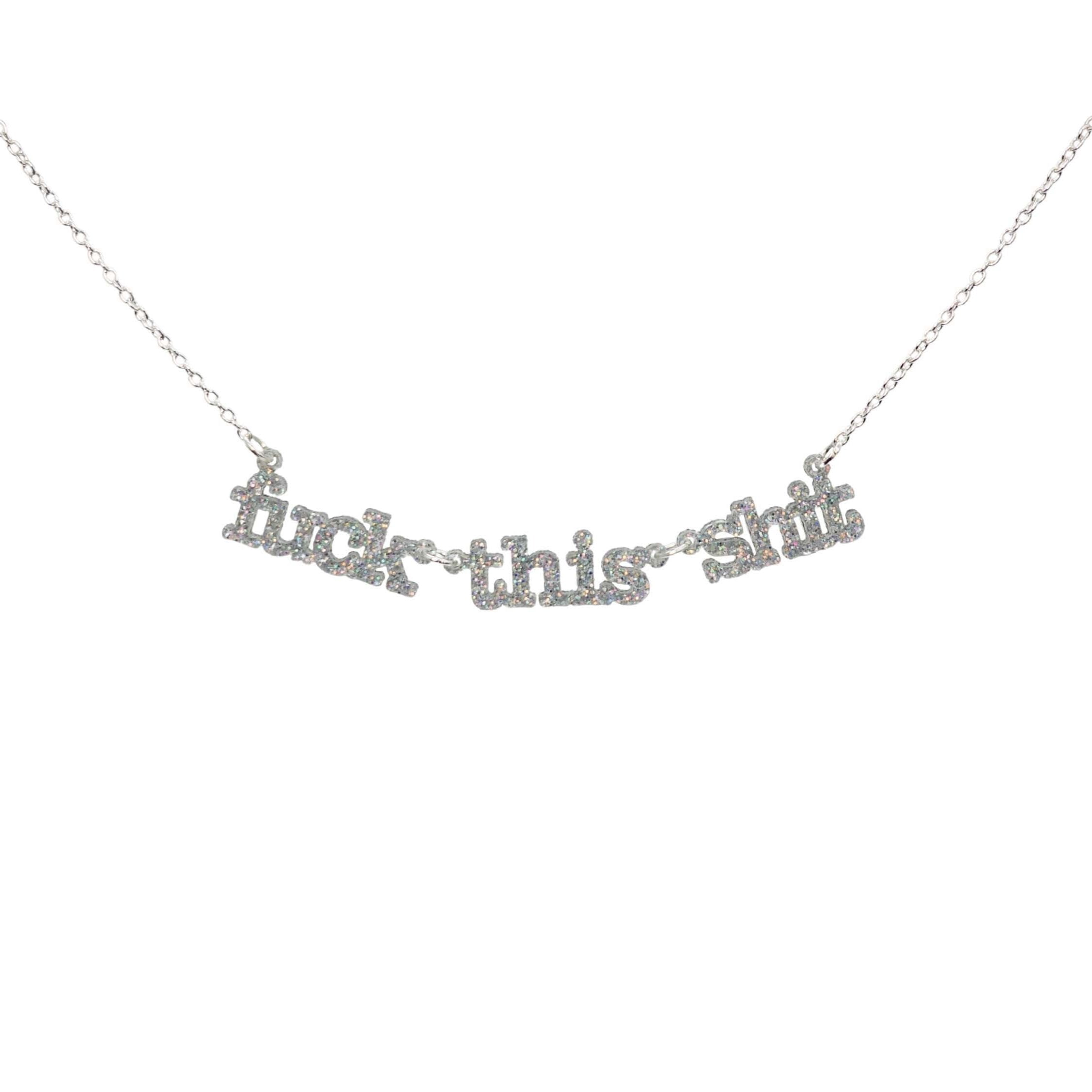 F*ck this sh*t necklace in silver glitter shown hanging against a white backround. 