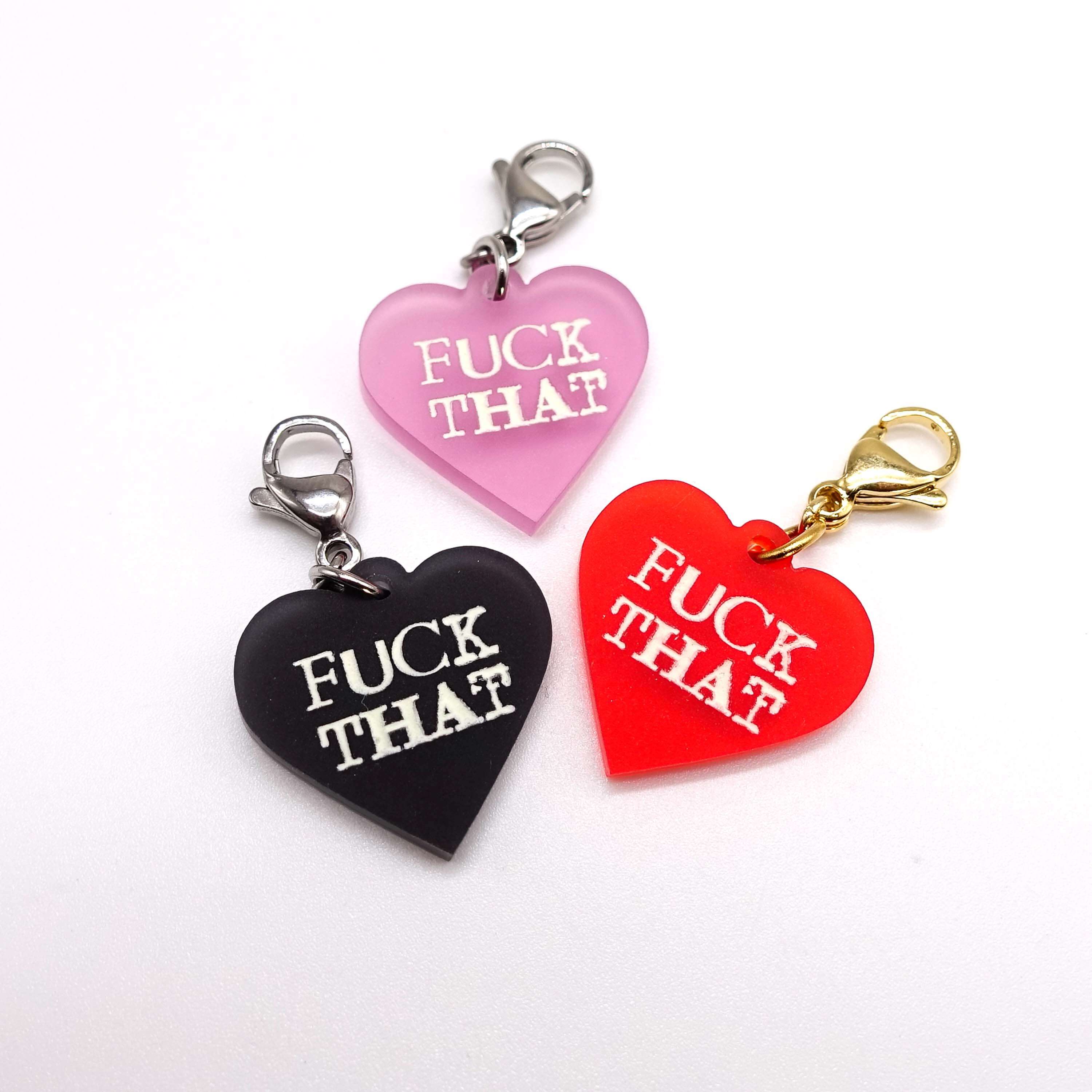 Heart charms etched and hand-painted with the words Fuck That  in glow in the dark pigment. 