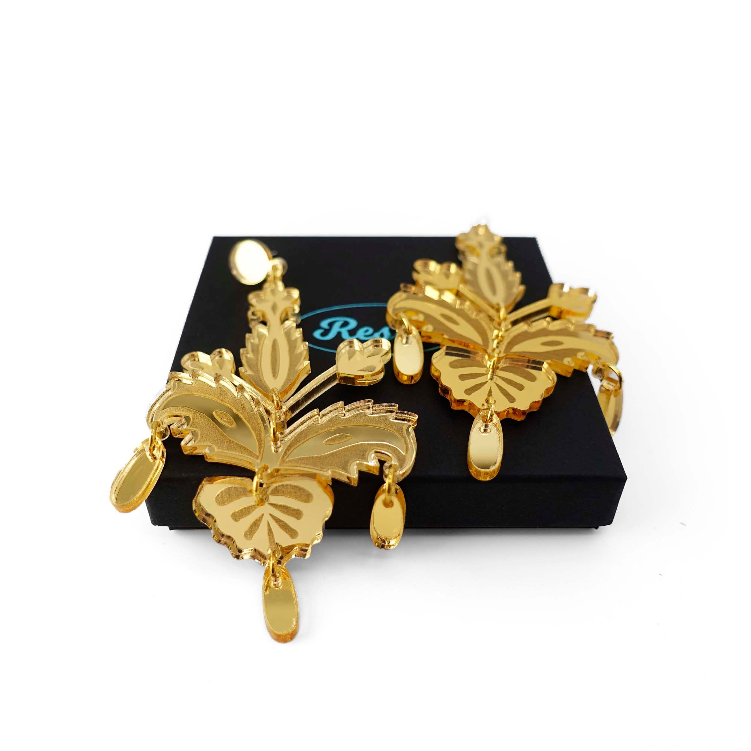 All gold festive drop statement earrings shown on a Wear and Resist gift box. 