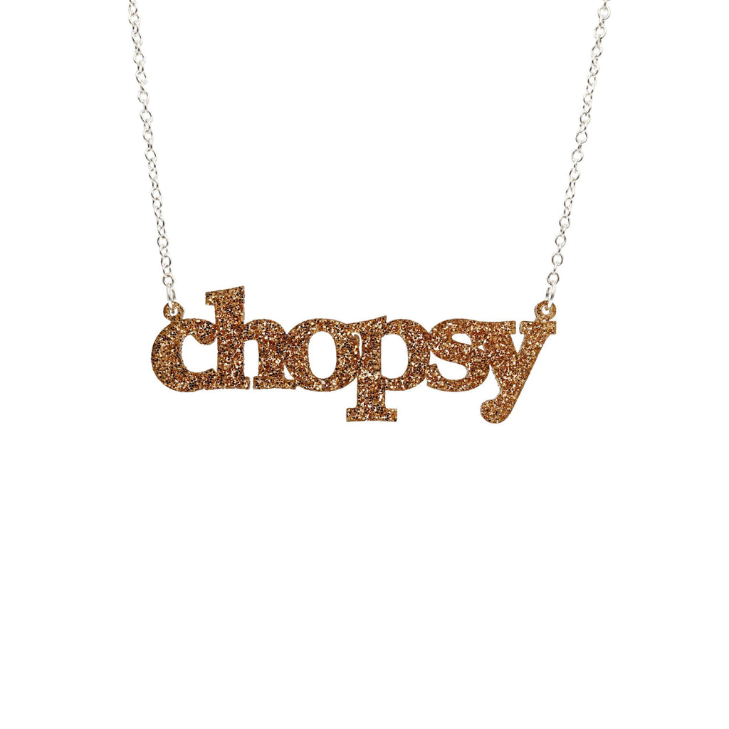 Gold glitter Chopsy necklace shown hanging against a white backround. 