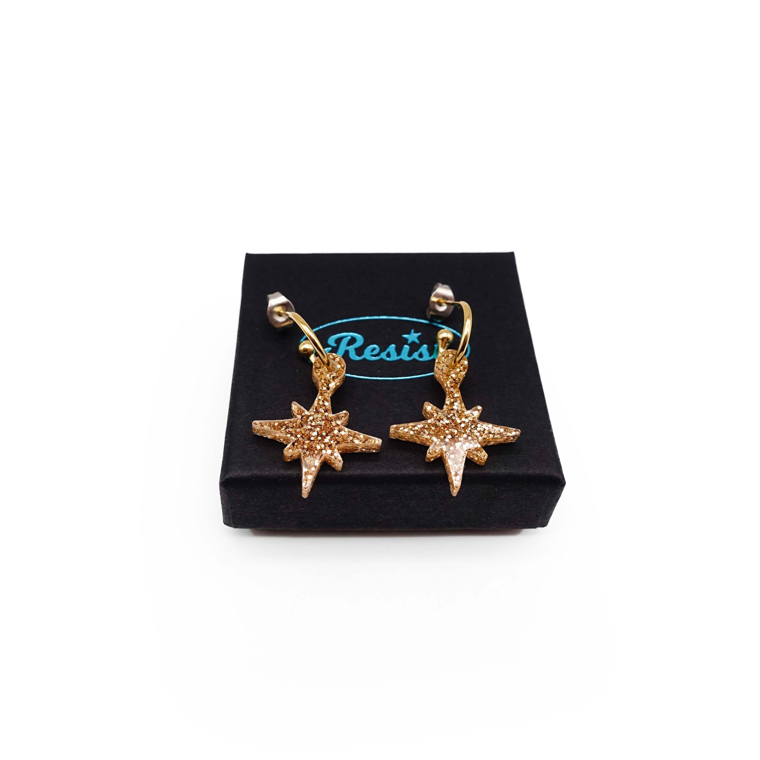 Gold glitter limited edition Festive Vintage Star earrings, shown on a Wear and Resist gift box.  