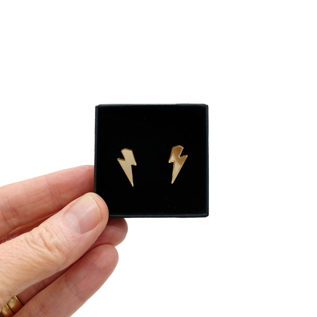 Tiny lightning bolt earrings in gold mirror.