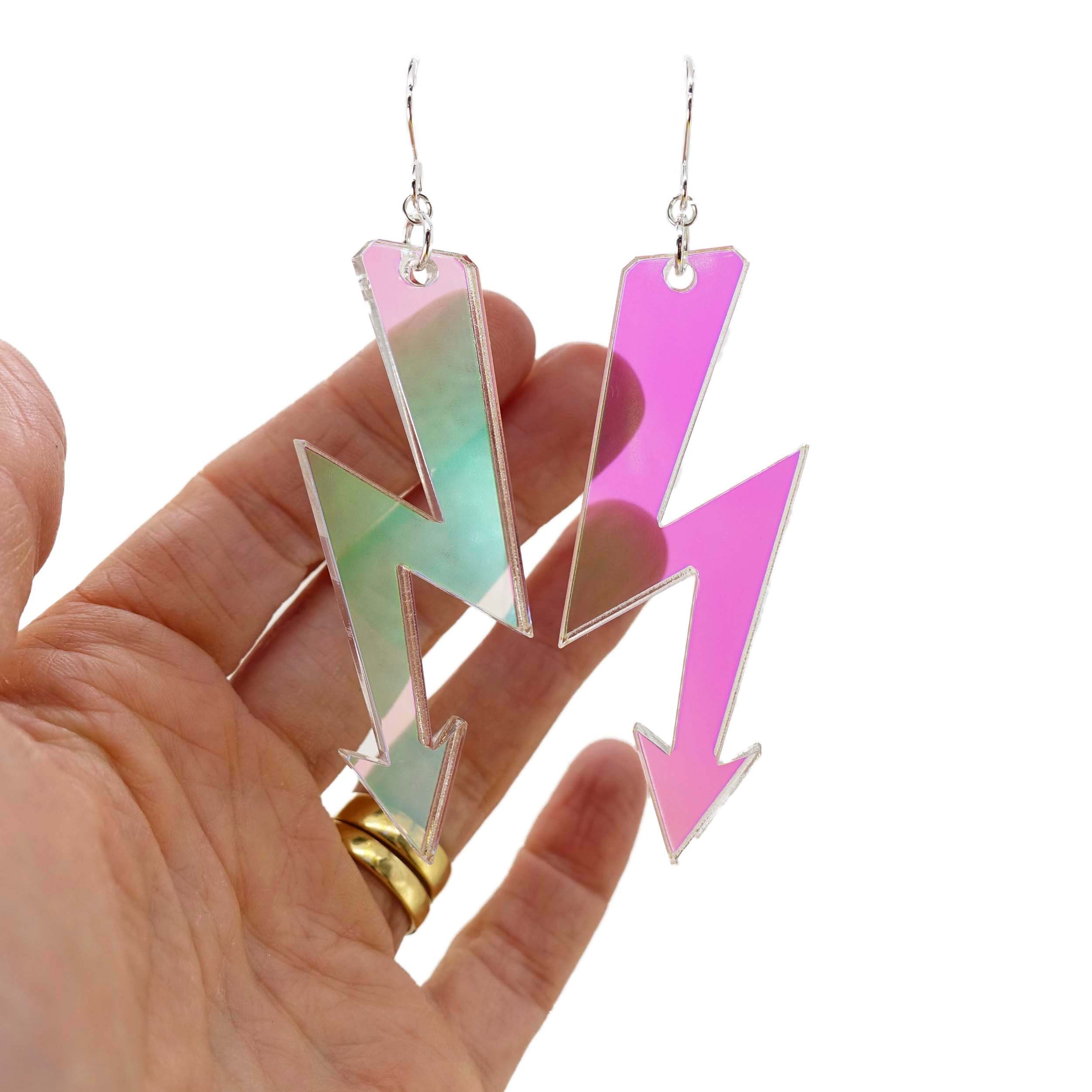 Iridescent High Voltage earrings shown against a white background with my hand behind to illustrate the transparency of the material. 