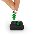 My hand holding one of a pair of naturalistic Holly earrings with red berries, the other one lying on a Wear and Resist gift box. 