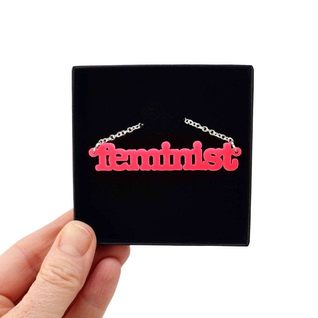 Hot pink Feminist necklace shown in a Wear and Resist gift box. 