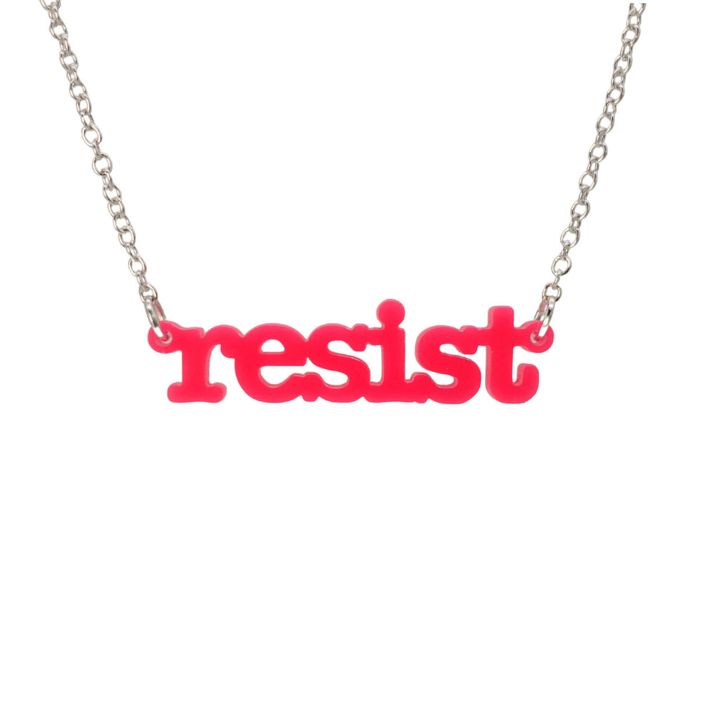 Hot pink Resist necklace in typewriter font hanging on a silver chain against a white background. 