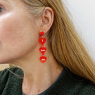 Sarah Day, founder of Wear and Resist, wears I love me heart drop earrings in hot red. 