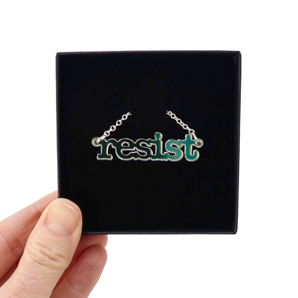Iridescent Resist necklace in typewriter font shown in a Wear and Resist gift box. 