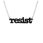 Matte black Resist necklace in typewriter font hanging on a silver chain against a white background. 