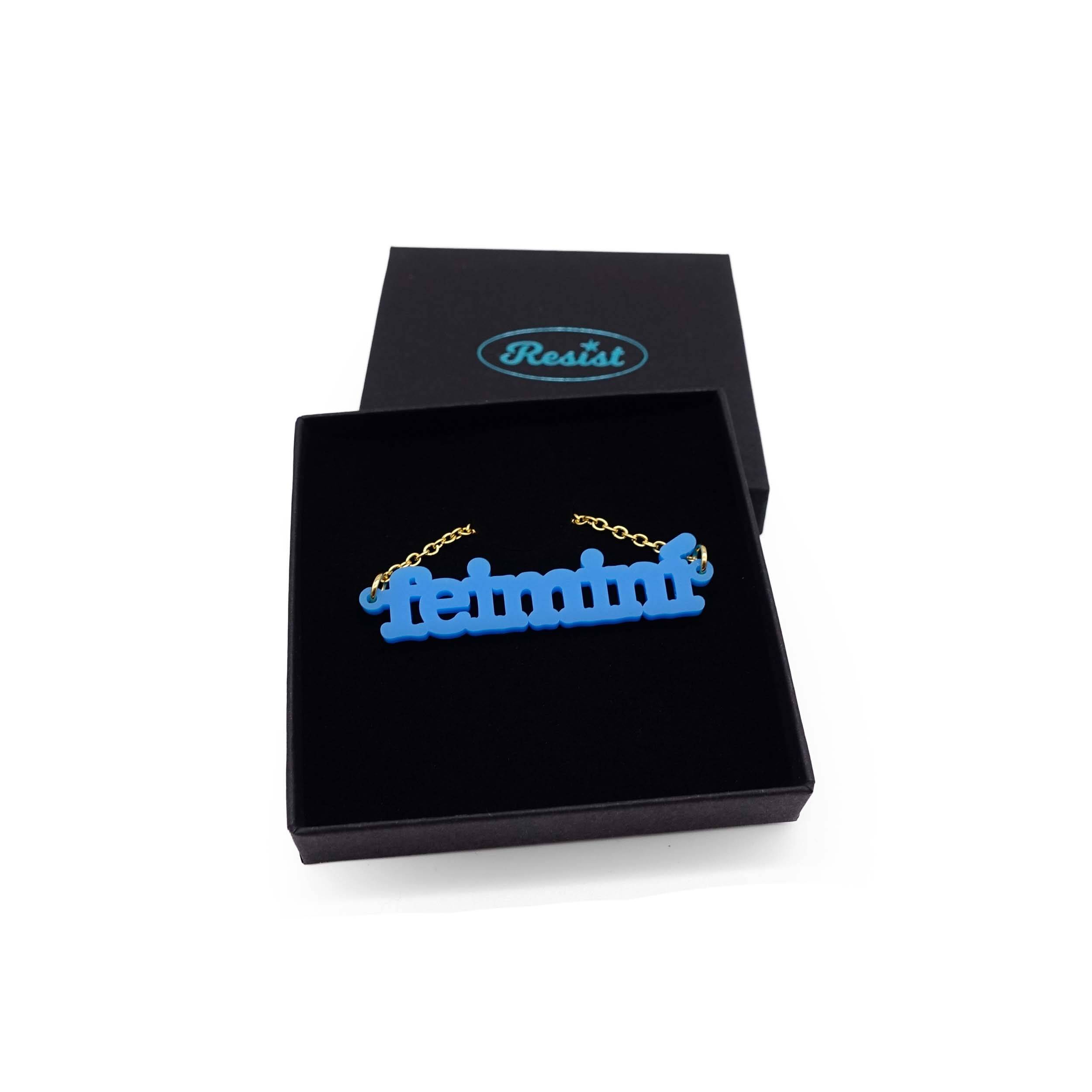 Irish Gaelic Feiminí necklace in matte bright blue, shown in a Wear and Resist gift box. 