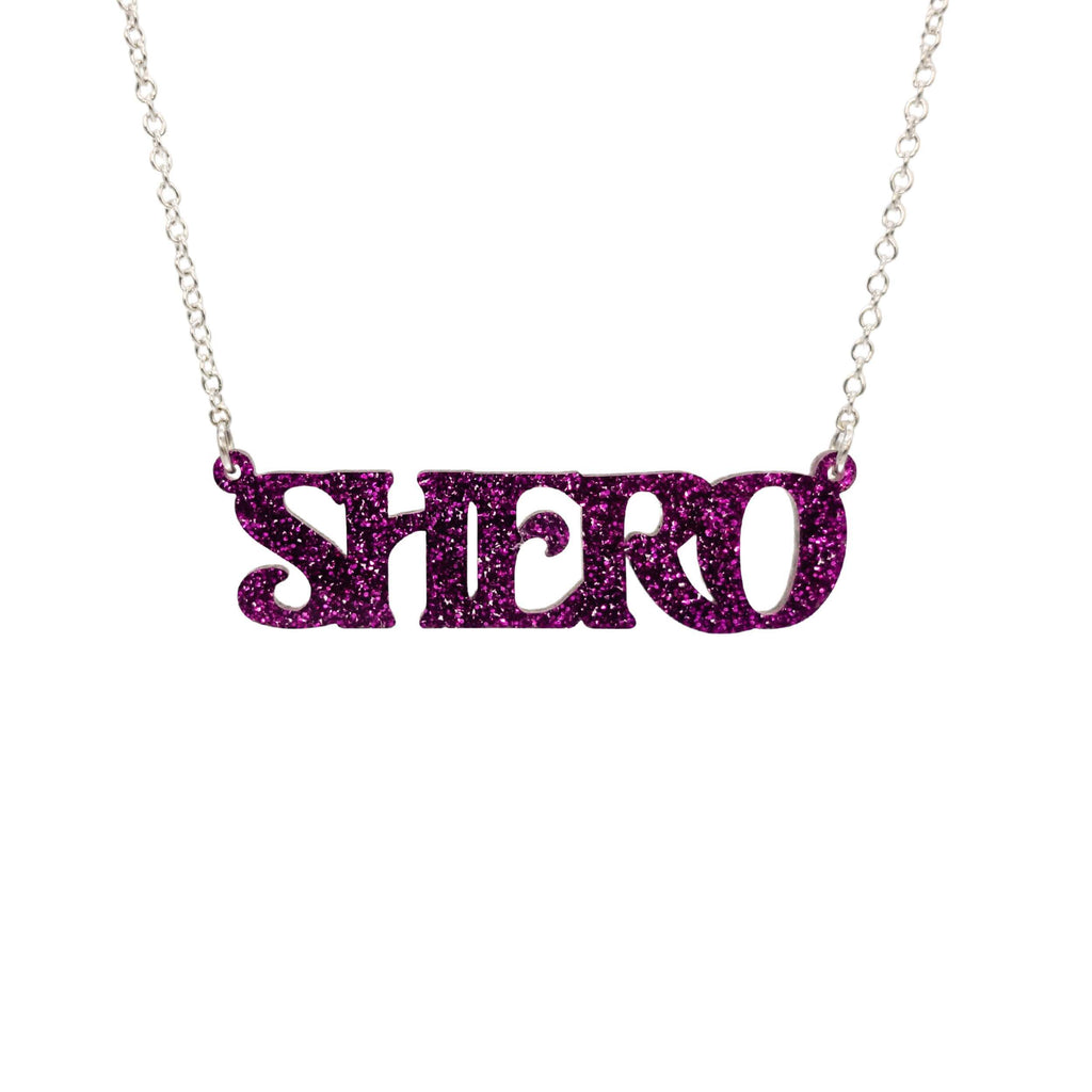 Purple glitter Shero necklace shown in a Wear and Resist gift box. 