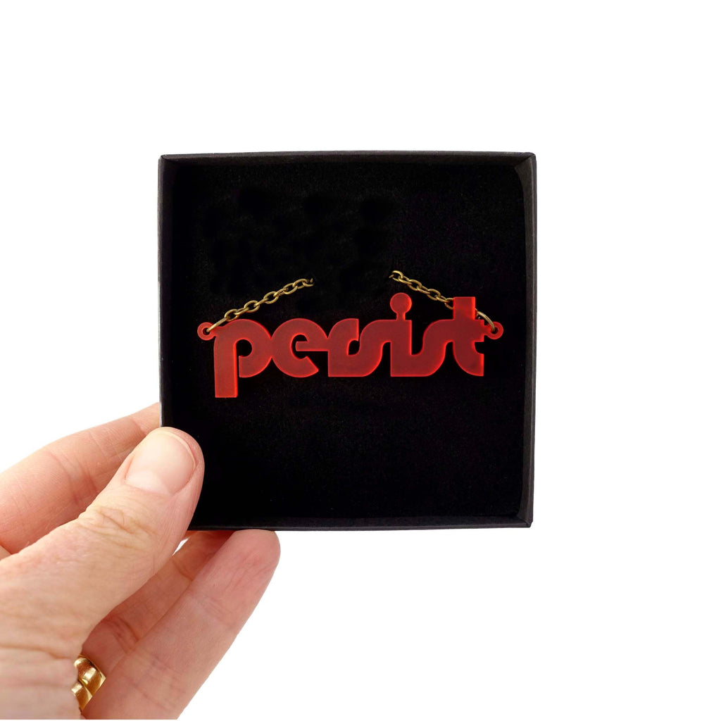 Chilli red disco Persist necklace shown held up in a Wear and Resist gift box. 