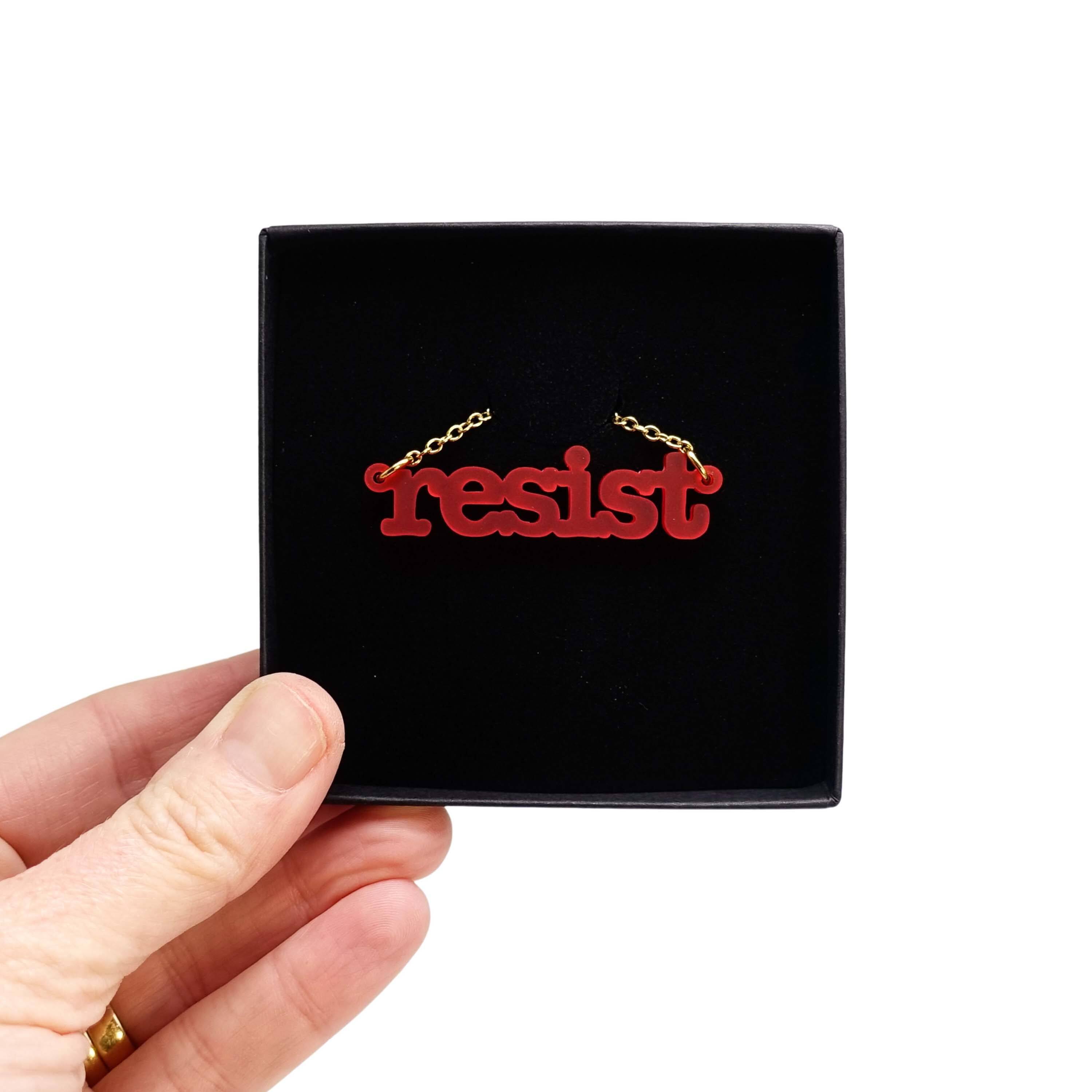 Typewriter Resist necklace in chilli frost shown held up in a Wear and Resist gift box. 