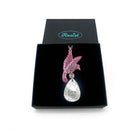 An acrylic pendant necklace with a pink bird holding a silver 'jewel' that says 'F*ck This'. Shown in a Wear & Resist gift box.