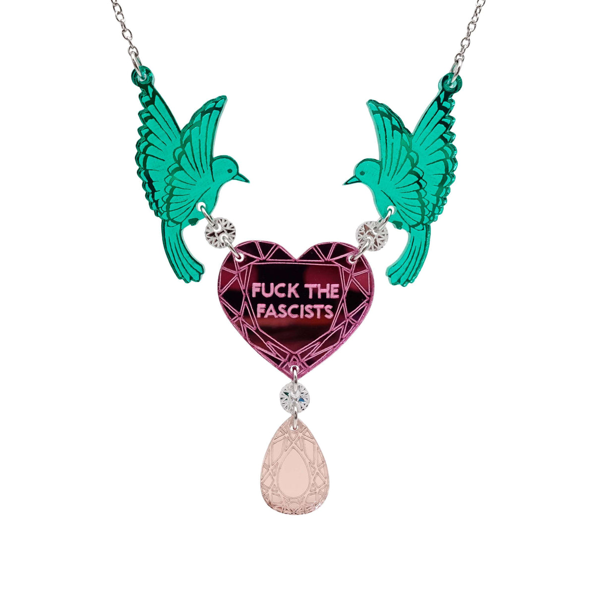 A mirror acrylic necklace with two green birds holding a pink heart that says 'Fuck the Fascists' with a rose gold 'jewel' hanging from the centre. 