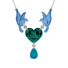 A mirror acrylic necklace with two blue birds holding a green heart that says 'Fuck these fucking fuckers' with a teal gold 'jewel' hanging from the centre. 