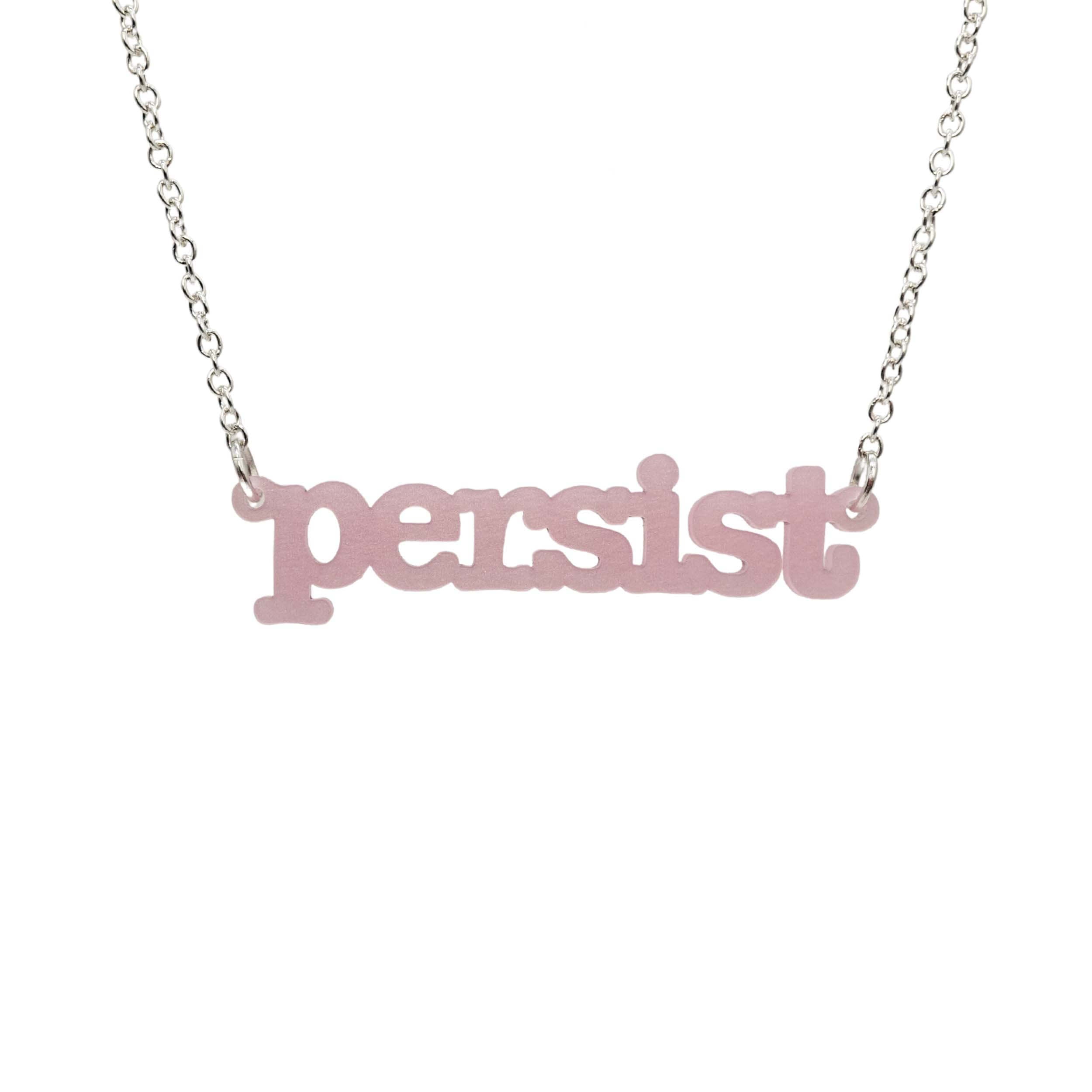 Shell pink Persist necklace in typewriter font hanging on a silver chain against a white background. 