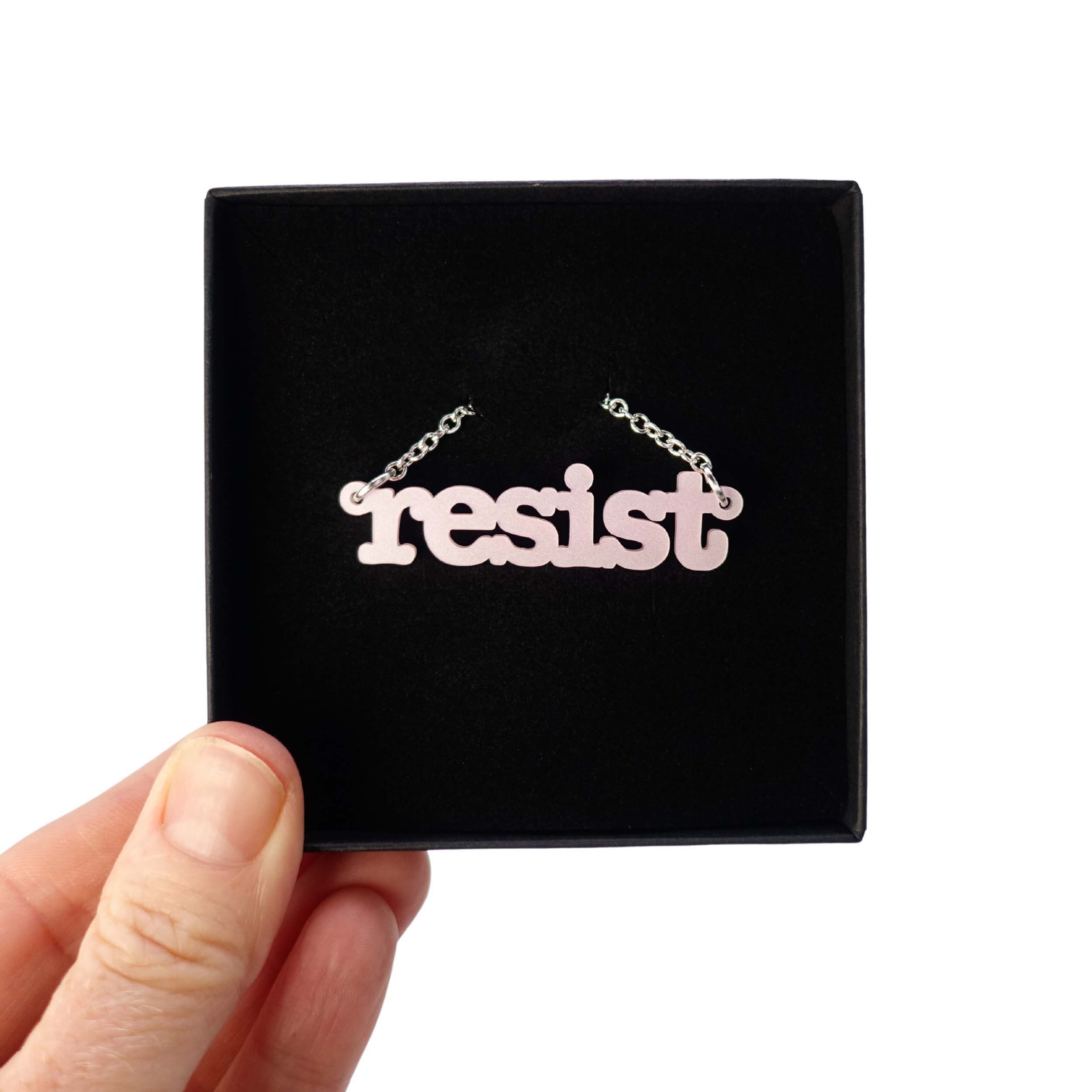 Shell pink Resist necklace in typewriter font shown in a Wear and Resist gift box. 