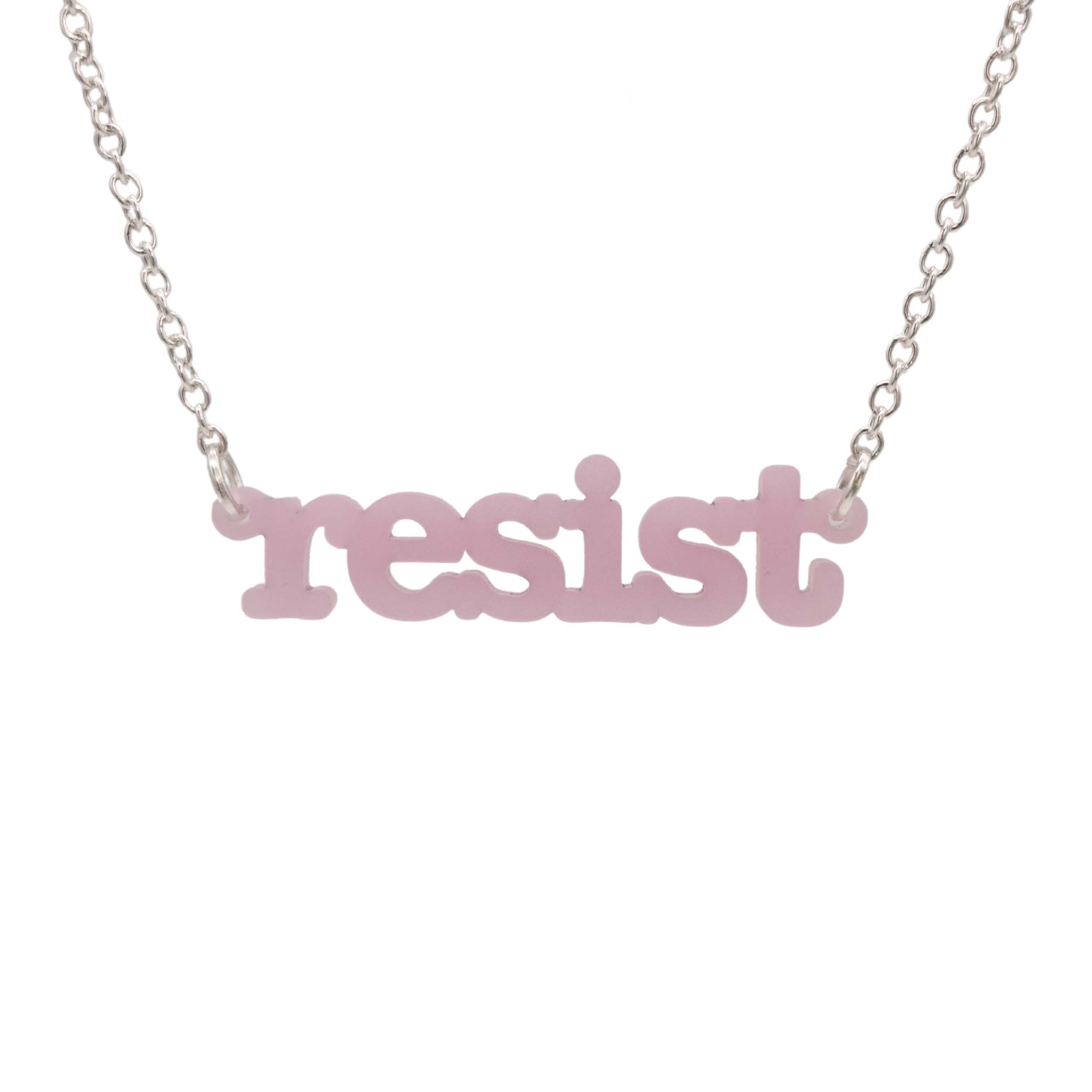 Shell pink Resist necklace in typewriter font hanging on a silver chain against a white background. 