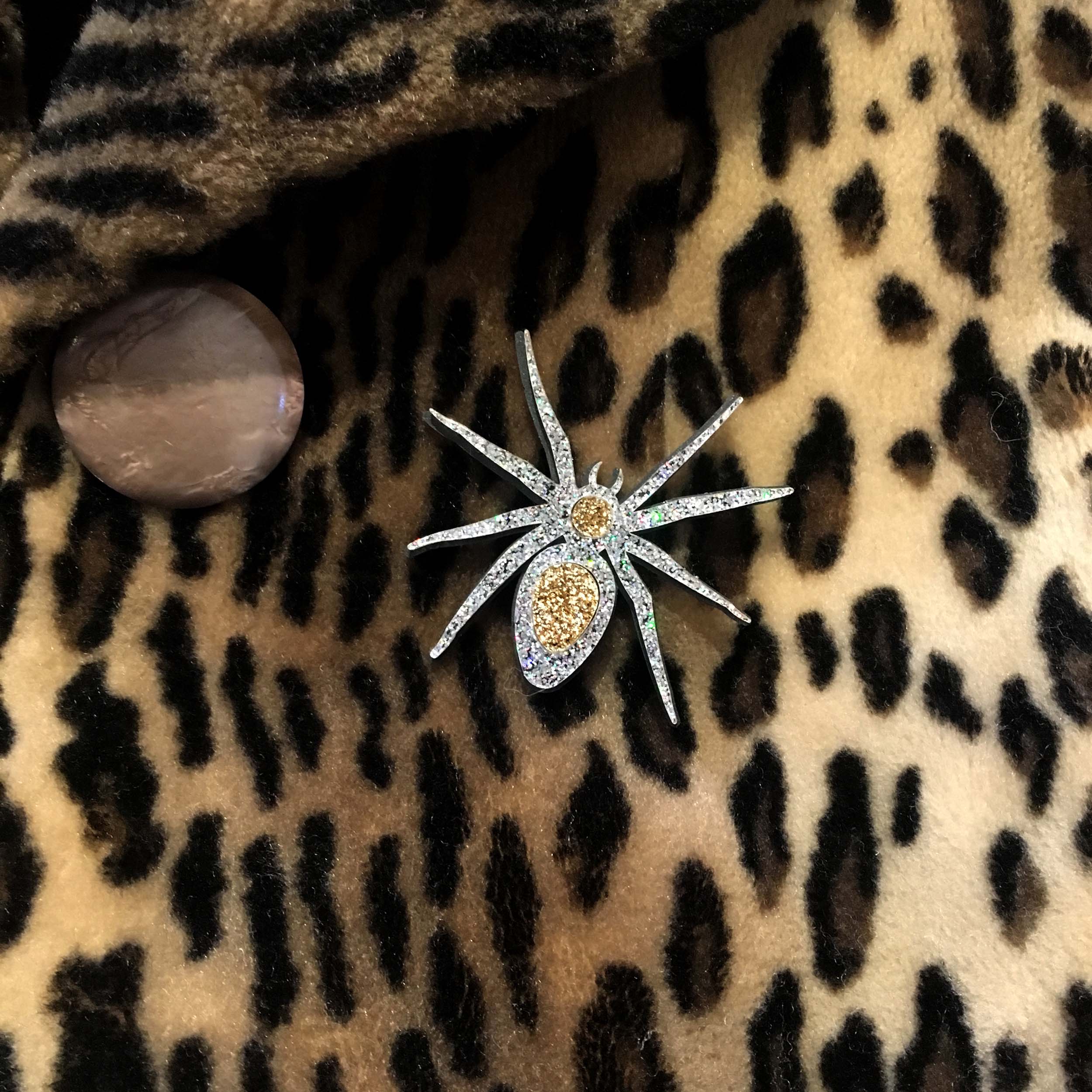 Silver Lady Hale Spider brooch shown worn on a leopard print coat. 
