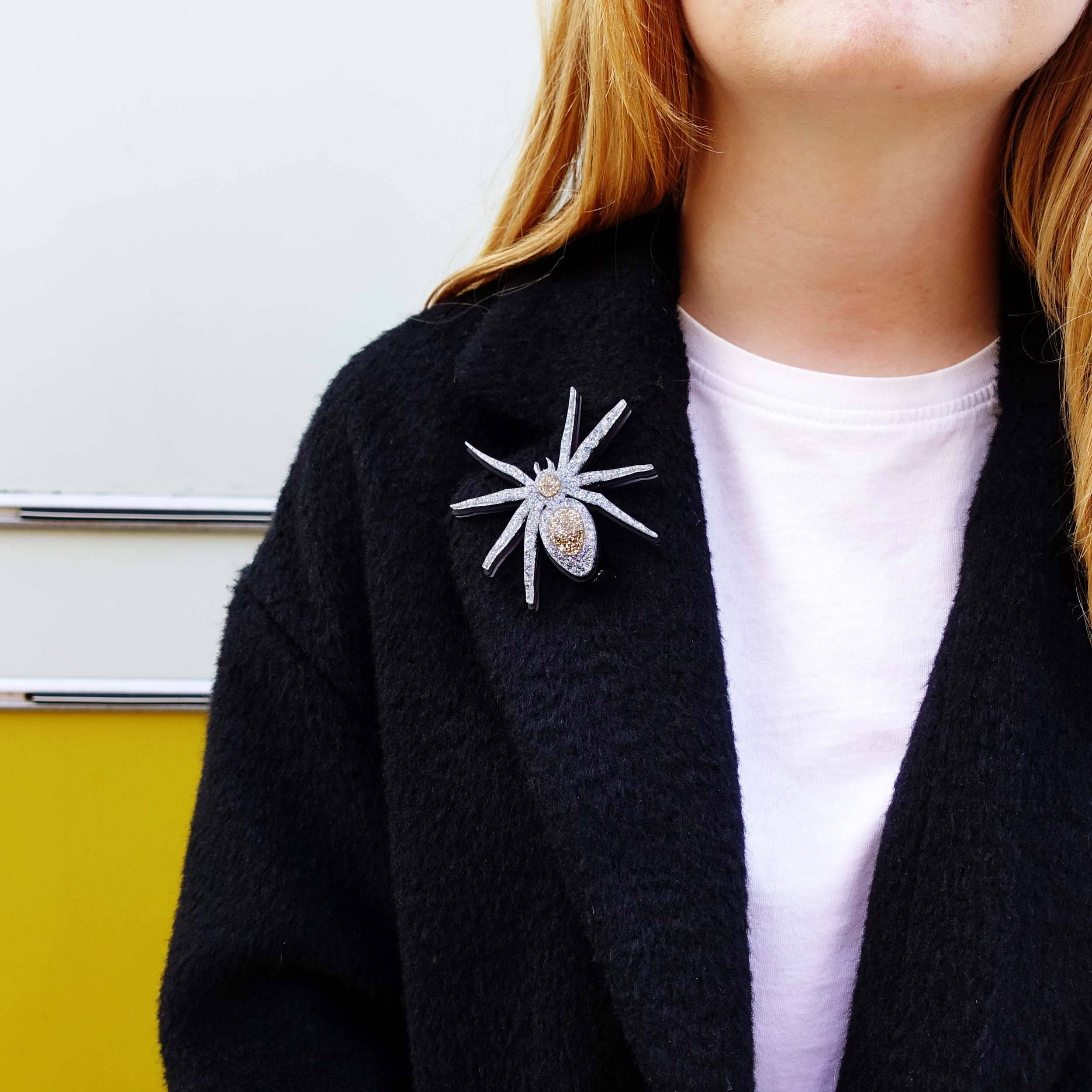 Eliza wears the All Hail Lady Hail Spider brooch on a black coat. 