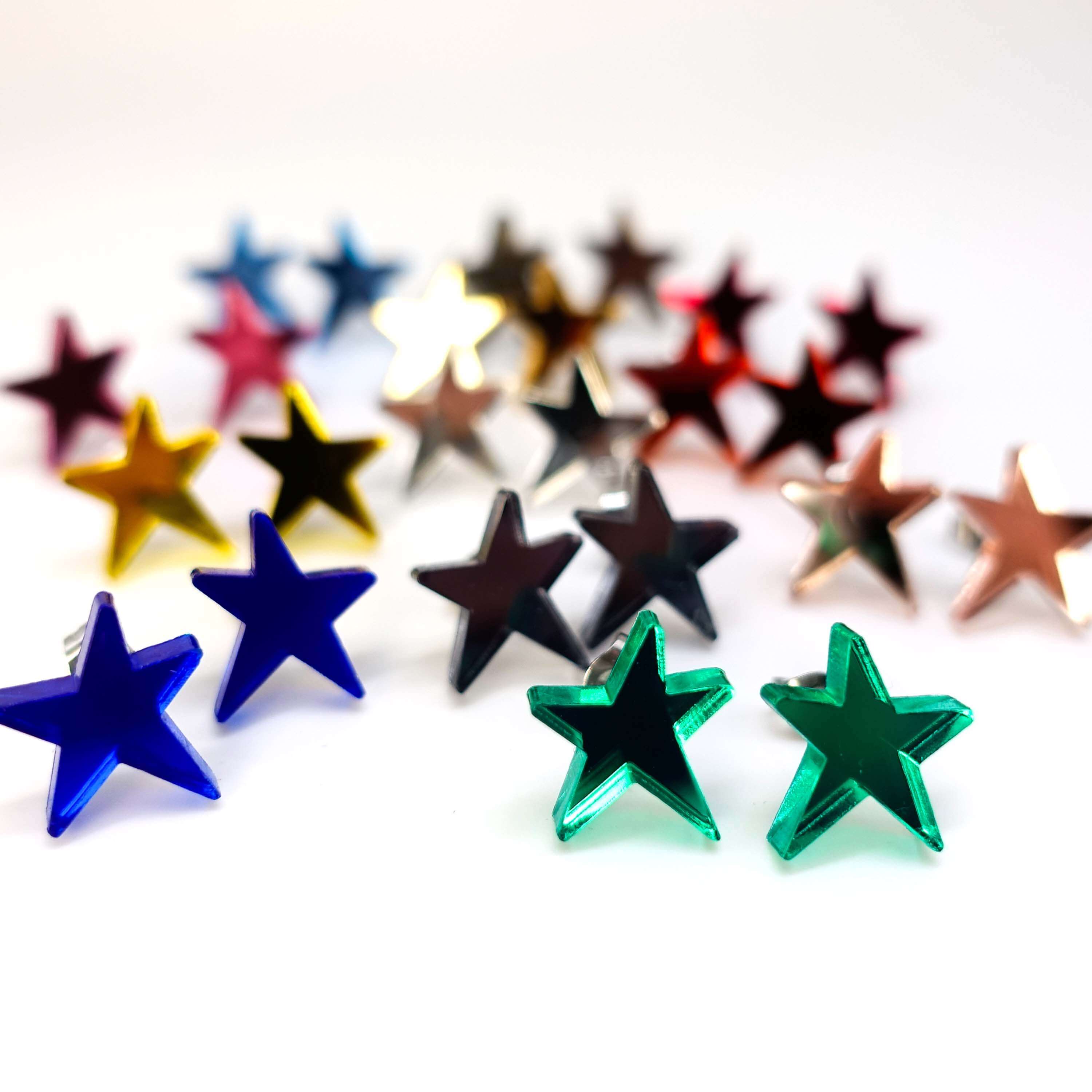 A group shot of all the funky Resist star earrings shown standing on a white surface. 