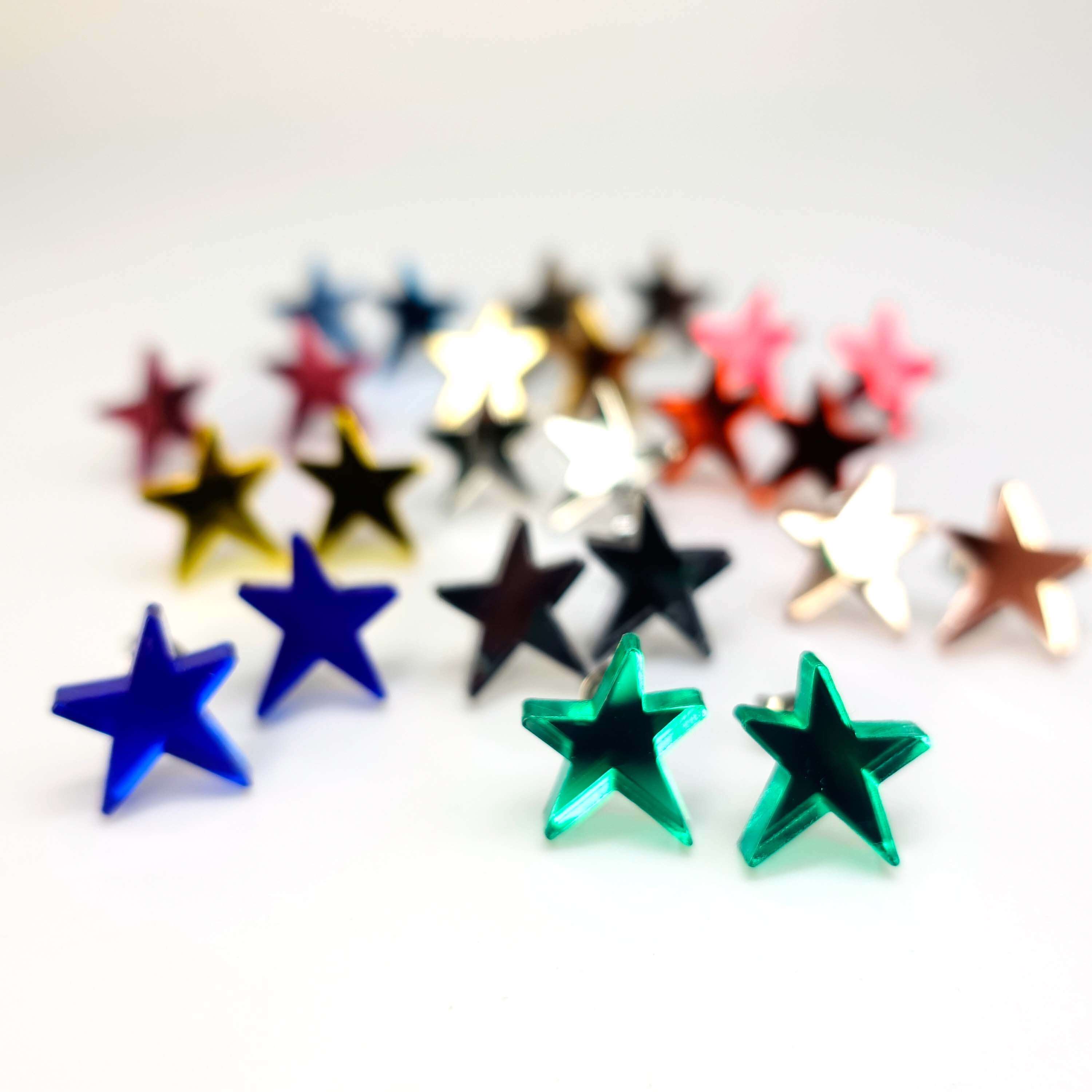 A group shot of all the funky Resist star earrings in different mirror colours shown standing on a white surface. 