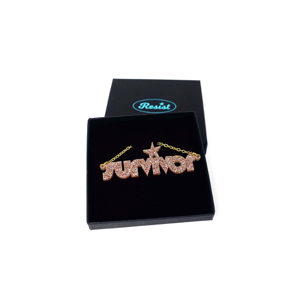Survivor necklace in pink fizz glitter shown in a Wear and Resist gift box. 