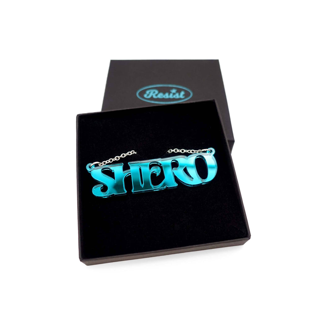 Teal mirror Shero necklace shown in a Wear and Resist gift box. 