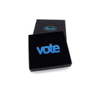 Vote brooch in bright matte blue shown in a Wear and Resist gift box. 