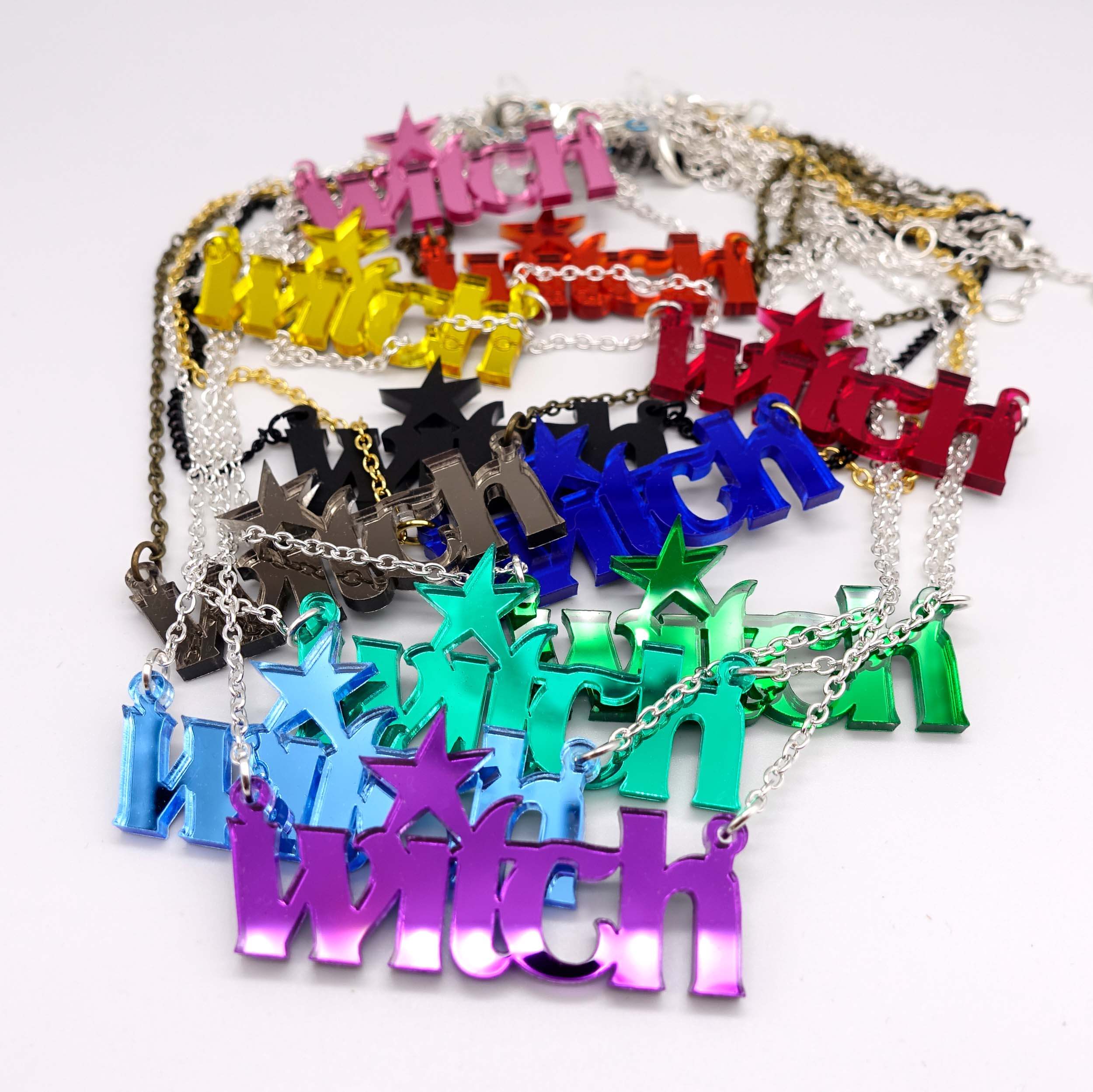 All of the Witch necklaces shown strewn together on a white background. 