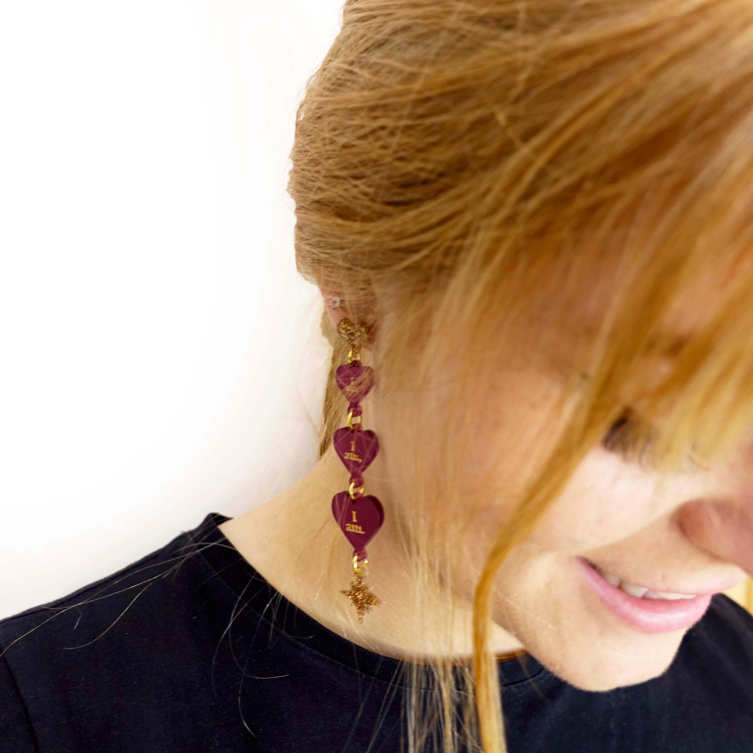 Eliza wears I am I am I am engraved heart dangling earrings with gold vintage stars. 