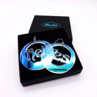 Hell Yes hoop earrings by Wear and Resist shown in a gift box against black so the colours of the iridescence show. 
