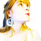 Model wears Hell Yes hoop iridescent earrings by Wear and Resist. 