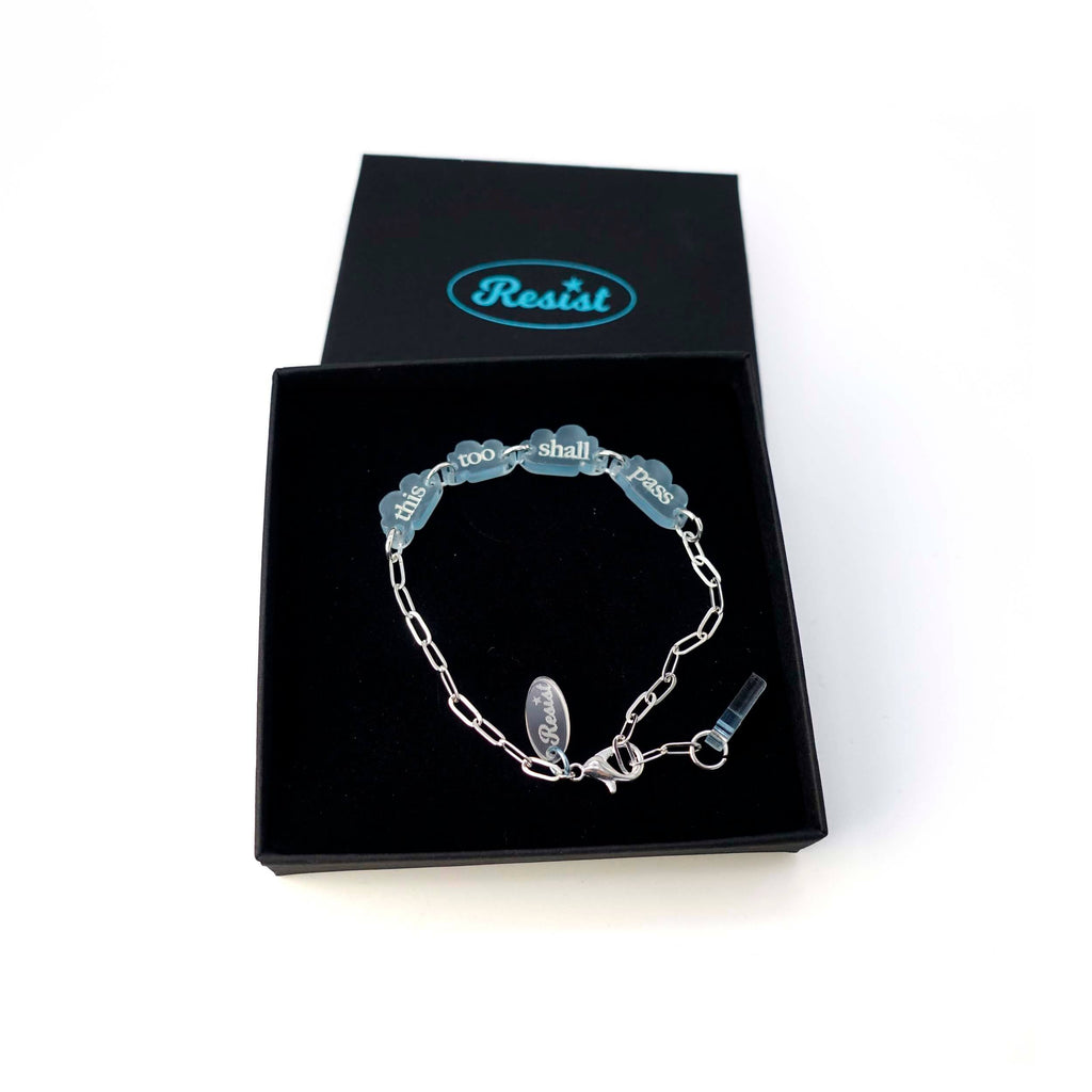 This too shall pass floating clouds silver bracelet shown in a Wear and Resist gift box. 