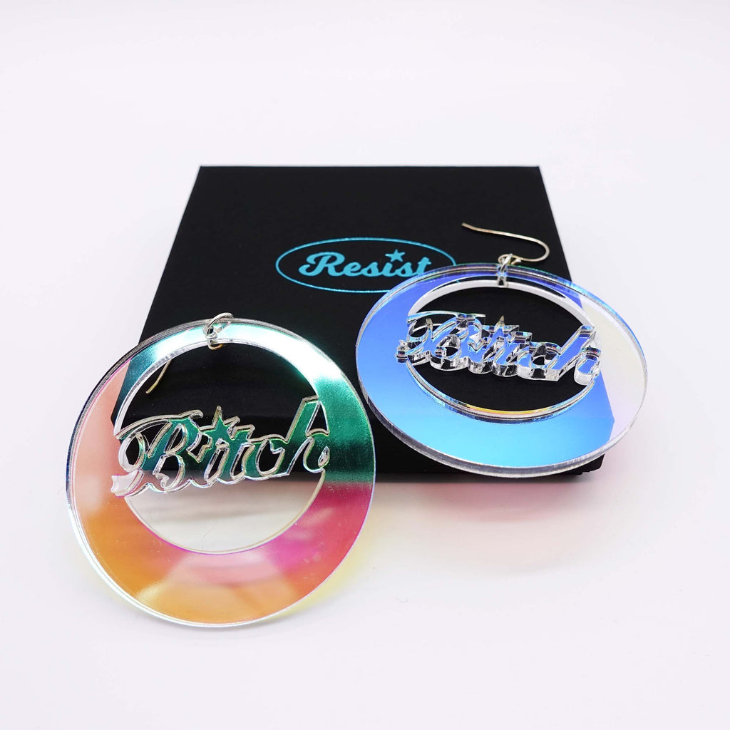 B*tch iridescent hoop earrings shown leaning on a Wear and Resist gift box. 