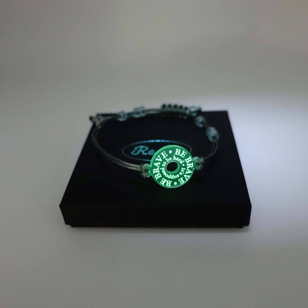 Glow in the dark Be Brave bracelet shown on a Wear and Resist gift box. 