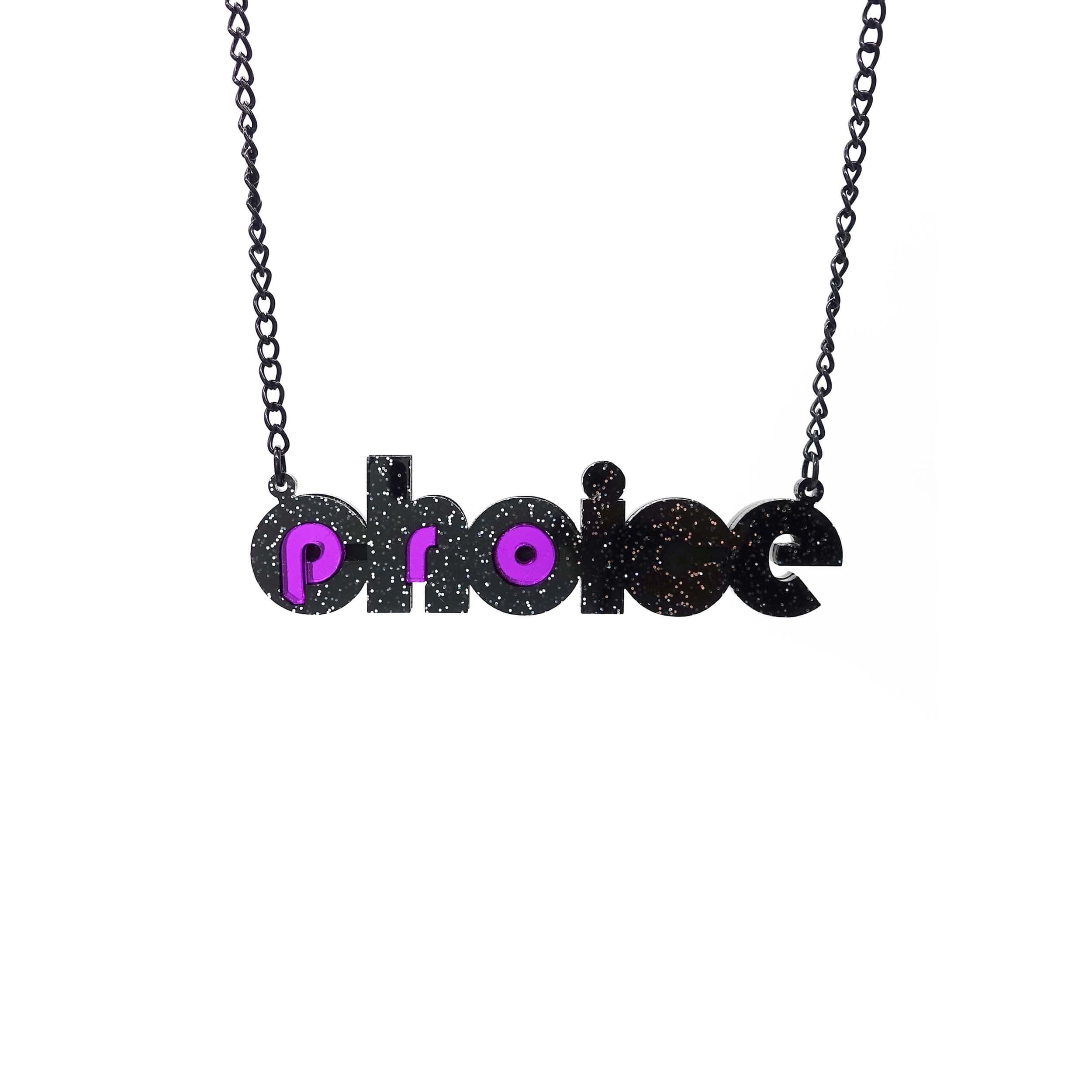 Black glitter and purple mirror Pro-choice necklace, shown hanging on black chain, designed by Sarah Day for Wear and Resist. £2 goes to Alliance for Choice who campaign  for Free, Safe and Legal abortions for anyone who needs them. 