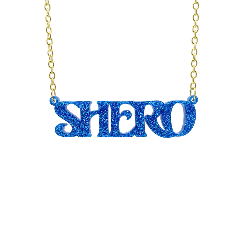 Blue glitter Shero necklace hanging against a white background. 
