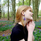 Model wears bluebell earrings in a bluebell wood. Designed by Sarah Day for Wear and Resist. 