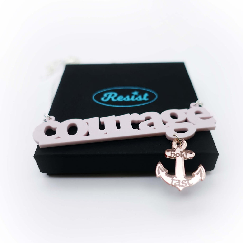 Courage necklace to benefit the RNLI and Women for Refugee Women in chalk pink with a rose-gold mirror anchor etched with the words 'hold fast,' shown on gift box. 