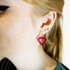 Eliza wears small transparent hot pink love heart hoop earrings. 