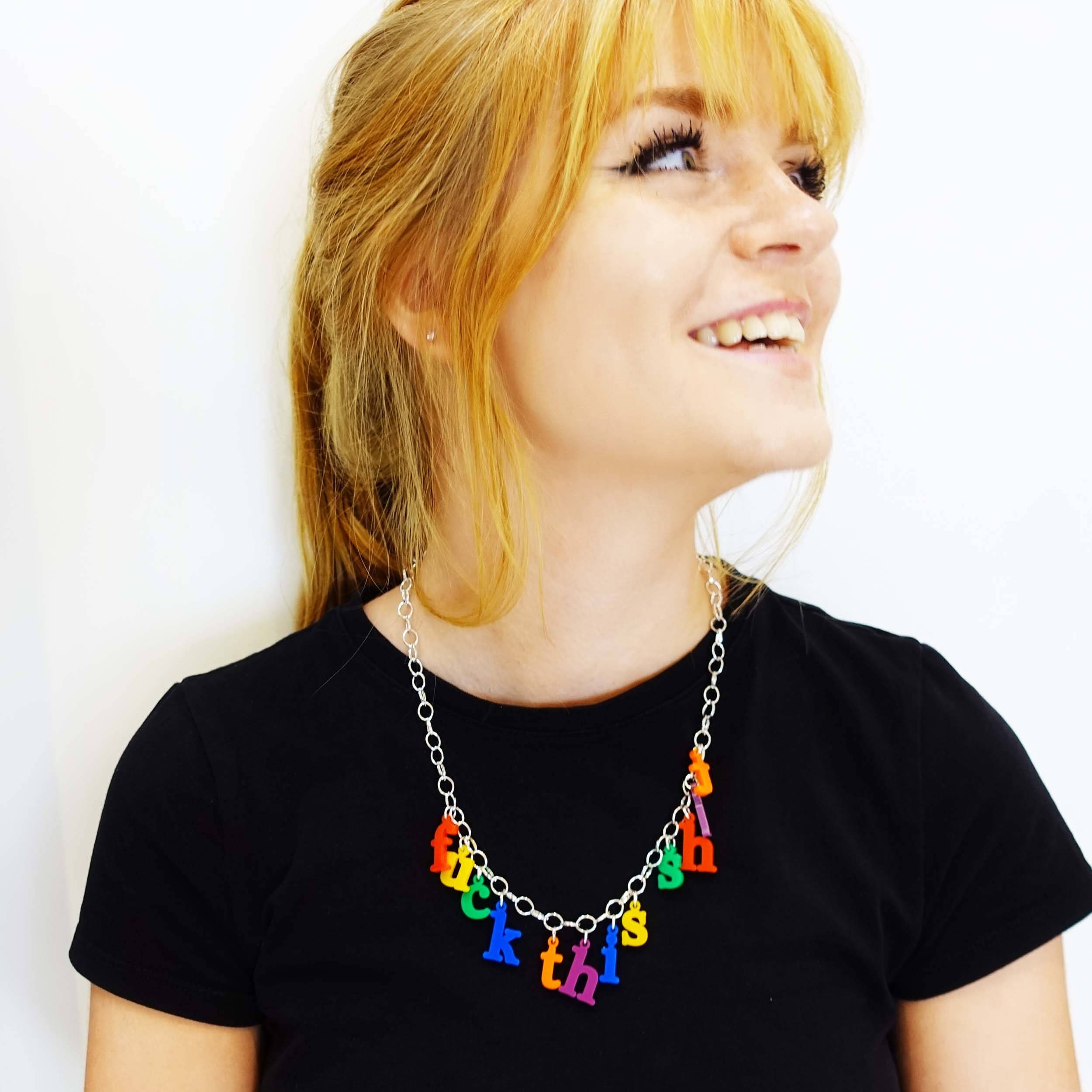 Model laughing wearing a F*ck this sh*t necklace in retro alphabet letters designed by Sarah Day for Wear and Resist.  